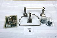 Photo shows a magnetic door stopper in chrome finish, a towel holder in brushed chrome with a semi-circular wire design, and a toilet paper holder in brushed chrome with a horizontal bar. Also included is a plastic bag containing mounting hardware and a sealed package with additional hardware.