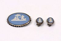 Oval brooch and pair of clip-on earrings showing blue jasperware with white relief and silver edges, top view