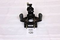 Front view of the Dremel table top accessory showing two handles, adjustable clamp mount, Dremel logo on base, and mounting hole.