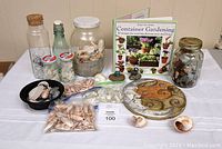 Complete lot showing jars of sea shells, ocean glass, bottles, sparkle lights, garden stone, and Container Gardening book