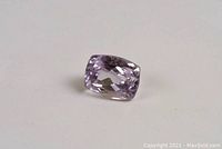 Photo of a single rectangular cushion cut amethyst gemstone showing light grayish purple color and facets reflecting light.