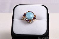 Front view of the ring showing the large central larimar stone surrounded by colorful mixed gemstones set in sterling silver.