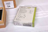 Samsung Galaxy S4 next to Kinovo Bluetooth hands-free car kit in packaging, both on white surface