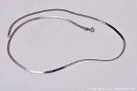 Full view of the 21 inch silver flat snake chain necklace laid out flat on a white background, showing clasp and chain texture.