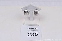 Photo of pair of silver hoop earrings on a white stand, showing front view and metal details.