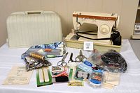 Singer Model 247 sewing machine with carrying case, manual and assorted sewing accessories including scissors, buttons, thread and tape on a table