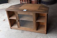 Front view of stained pine TV stand showing the wood grain top, central glass door, and flanking open shelves.