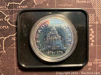Image of the silver coin obverse showing the Library of Parliament building and dates 1876-1976.