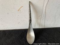 Full view of metal spoon showing smooth bowl and carved handle