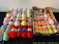 Top view of knitting wool skeins arranged in rows by color and brand.
