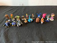 Overview of all 17 assorted toy figures arranged in a single row on a black surface.