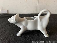 Side view of white ceramic cow creamer showing detailed features and open cavity for cream.