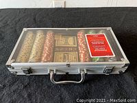 Poker set in closed aluminum case with clear lid showing poker chips, playing cards, and dealer button inside