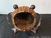 Front view showing the frog's open-mouthed wicker body with cast iron round eyeballs and legs