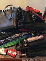 Overview of assorted handbags, umbrellas stacked and two Canada card holders visible.