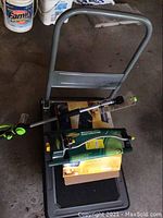 Gray metal folding hand cart with plastic platform and garden accessories on it