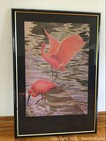 Full view of the framed art showing two red birds in water with reflections and black-gold frame.