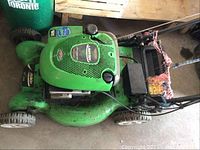 Top view of the green Lawn Boy push lawn mower showing the Briggs & Stratton 4.75 HP engine cover with brand stickers and black control handles with wired connection.