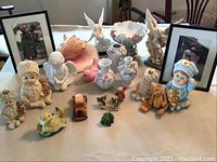 Full view of all decorative items and framed artworks arranged on table, showcasing various figurines, vases, seashell, and two framed photos.