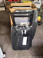 Folded metal frame black padded folding chairs stacked upright showing backside and seat structure.