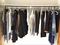 Photo showing a rack of assorted clothing garments in various sizes and styles, mostly jackets and tops hanging on plastic hangers.