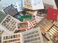 Overview of multiple open stamp albums and loose pages spread out