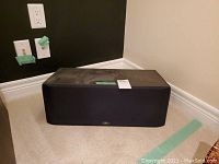 Full view of the black centre channel speaker with fabric grille and Paradigm emblem at bottom center.