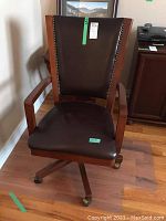 Front view of brown leather office chair with brass nailhead trim and wooden frame.