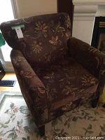 Front three-quarter view of the brown floral upholstered chair showing tapered legs and patterned fabric