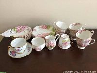 Full set of Royal Albert china pieces in Blossom Time pattern including cups, saucers, plates, creamer, and sugar bowl with floral design and gold trim on display.