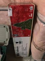 Box of 7.5 foot artificial Christmas tree with Christmas-themed red packaging showing a photo of the tree and product details.