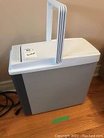 Front and side view of Koolatron P20 car drink cooler showing white plastic body with grey side panel and carry handle.