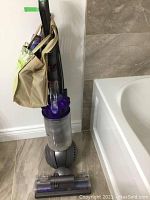 Full view of Dyson Ball upright vacuum cleaner showing main body, dust canister, and attached accessories.
