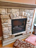 Front view of electric fireplace with stone face showing detailed stone arch and glass firebox.