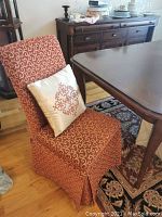 Single dining chair placed by dining table with decorative cushion on seat. Shows fabric pattern and chair shape.