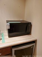 Front view of black Panasonic microwave oven on countertop, showing overall shape and control panel