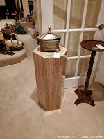 Front view of hexagonal stone pedestal on carpeted floor in room