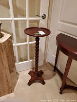 Full view of the wooden plant stand highlighting the twisted central column and tripod base.