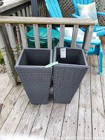 Two tall, dark gray resin wicker-style rectangular planters standing side by side on a wooden deck.
