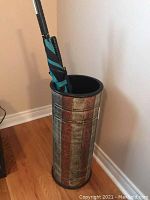 Overall view of the umbrella stand holding one umbrella inside.