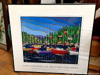 Full view of framed art print showing harbor with colorful boats and forested shoreline.