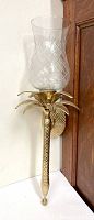 Single brass and glass wall candle sconce with etched diamond pattern glass shade shown from side angle against a wall.