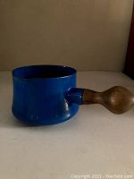 Blue enamel pot with teak handle shown from side