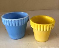 Blue and yellow flower pots side by side on a shelf.