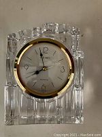 Front view of Seiko clock in clear glass case showing clock face and gold trim.