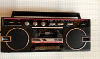 Top view of the front panel of the vintage Pulser boombox showing speakers, control knobs, cassette tape door and radio tuner.