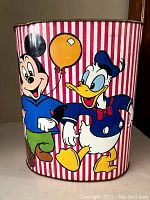 Front view of the metal waste can showing Mickey Mouse and Donald Duck on striped red and white background