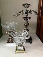 Full view showing two crystal cut glass dishes on decorative metal and stone bases and an ornate metal stand with hooks.