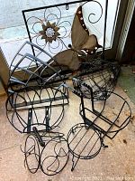 Eight metal garden decor pieces shown including a butterfly, flower wall decor, a frog stake, an insect stake and four curved metal brackets.