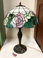 Full view of Tiffany style lamp with stained glass shade showing pink flowers, green leaves, and white sections